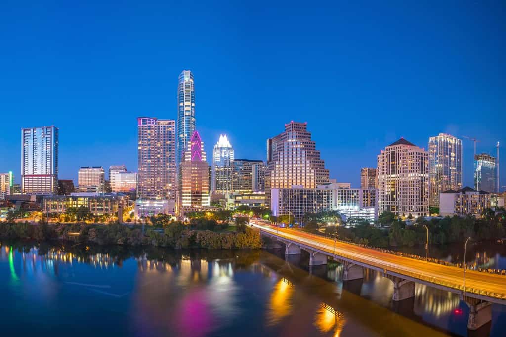 Downtown Austin from the perspective of a bank overlooking the river and. a bridge.