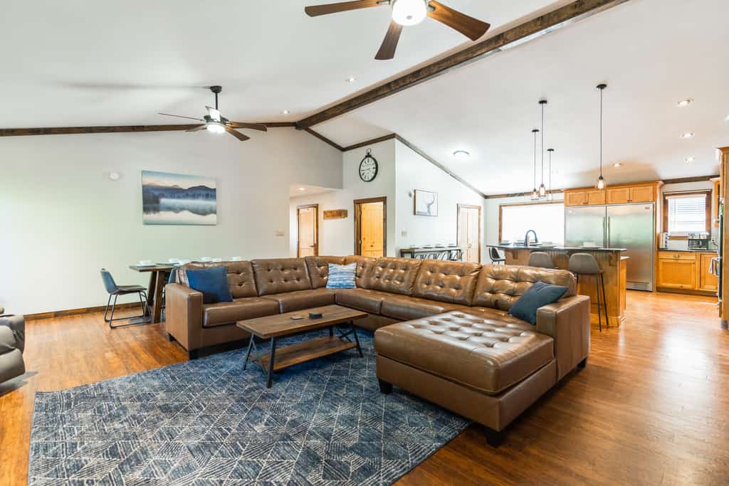 A large living room with a u-shaped brown leather sectional sofa