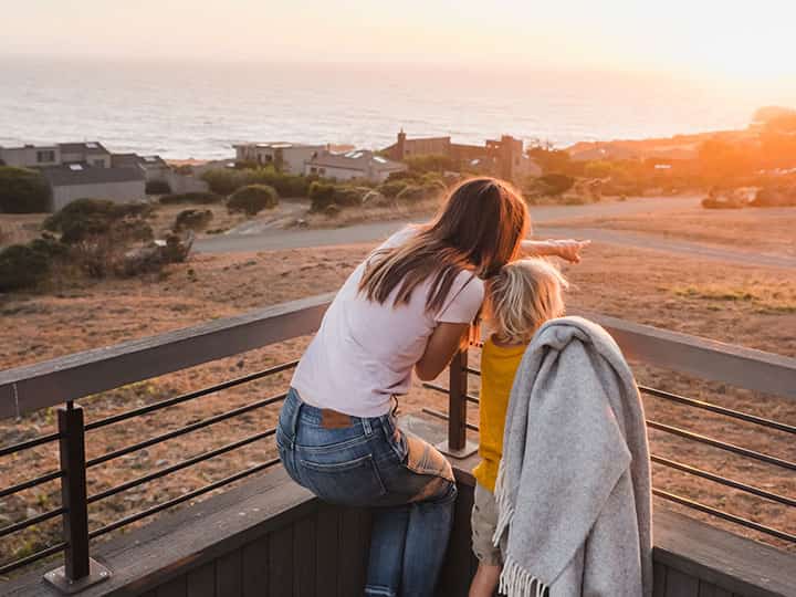 mother points out something in the distance to child on balcony of vacation rental