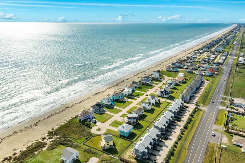 A drone shot of the Galveston, TX coastline lined by homes and the ocean.