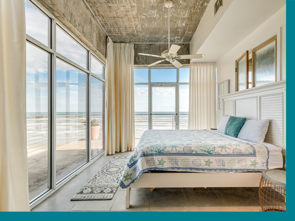 bedroom in Galveston Texas with glass windows and a sunny beach in the background