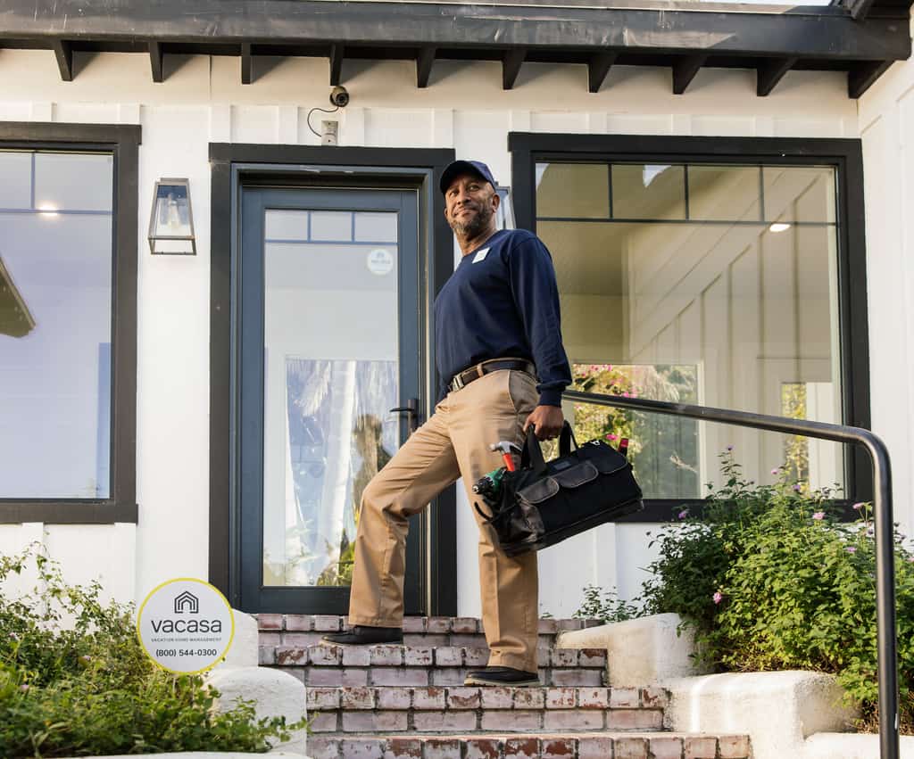 Man holding a tool bag in front of a vacation rental.