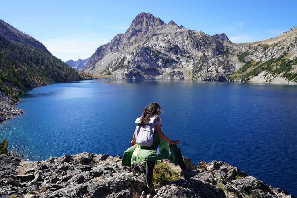 A woman hiking over a rock near a large alpine lake in McCall, ID.
