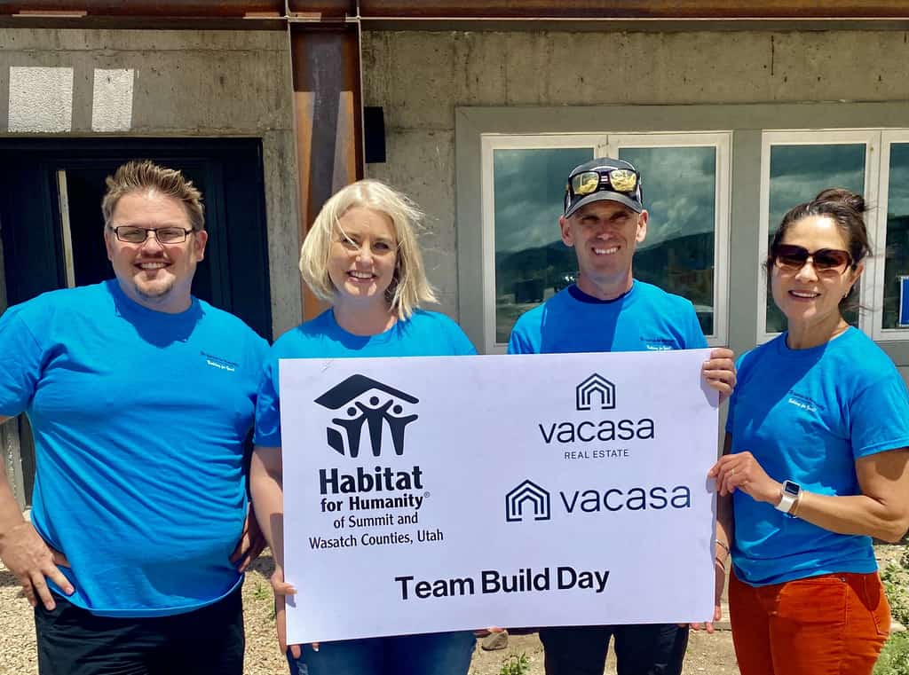 Four Vacasa employees holding up a Habitat for Humanity board.