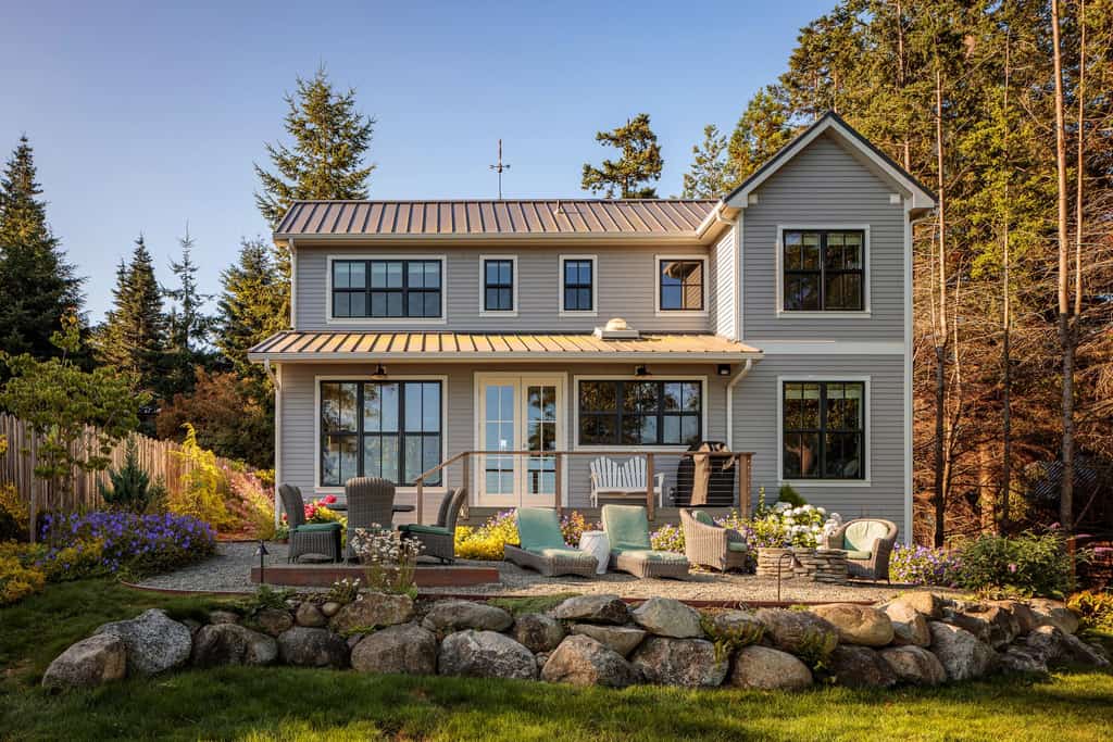 Grey modern home with gravel patio and landscaped yard