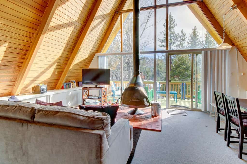 Big Bear Lake, CA a-frame vacation rental featuring floor-to-ceiling windows and a wood-burning fireplace
