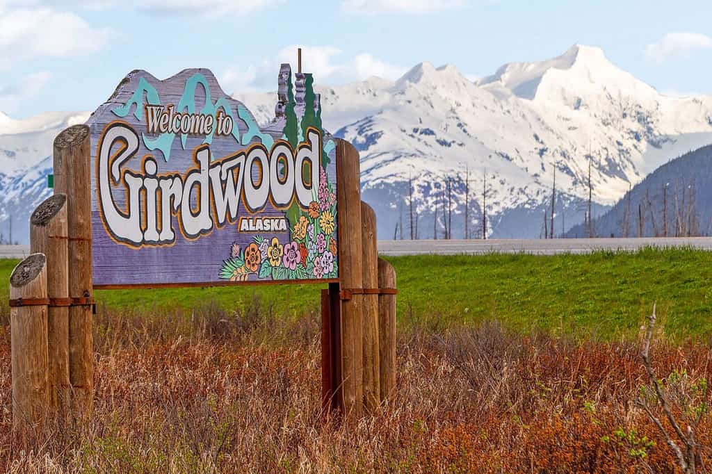 a Welcome to Girdwood, AK sign, with a snowy mountain backdrop