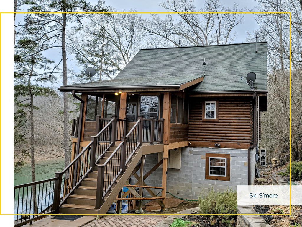 A cabin built on a slope  with a flight of stairs to the front door by a river.
