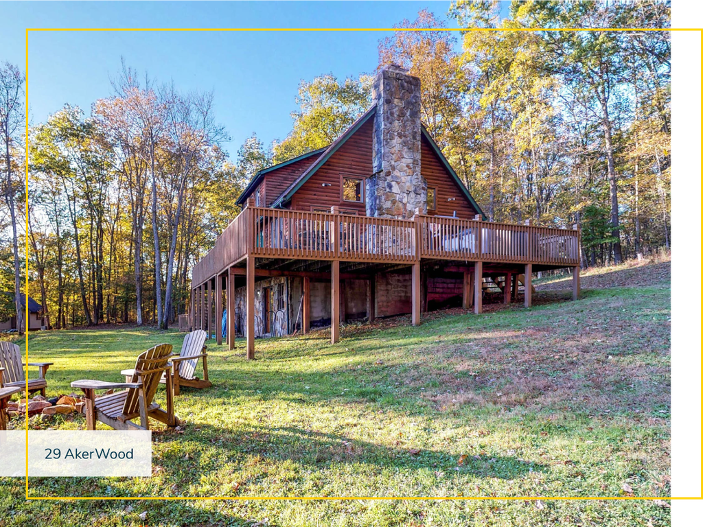 Wood cabin on an uphill slope with an outdoor fire pit and adirondack chairs.