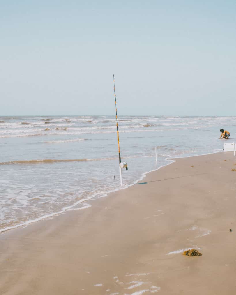 Image of a fishing road fishing in the ocean with a guy to the left.