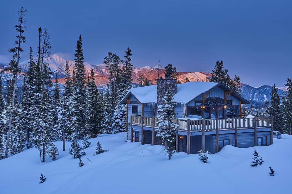 Beautiful view of Big Sky, MT vacation home surrounded by snowy pines and mountains