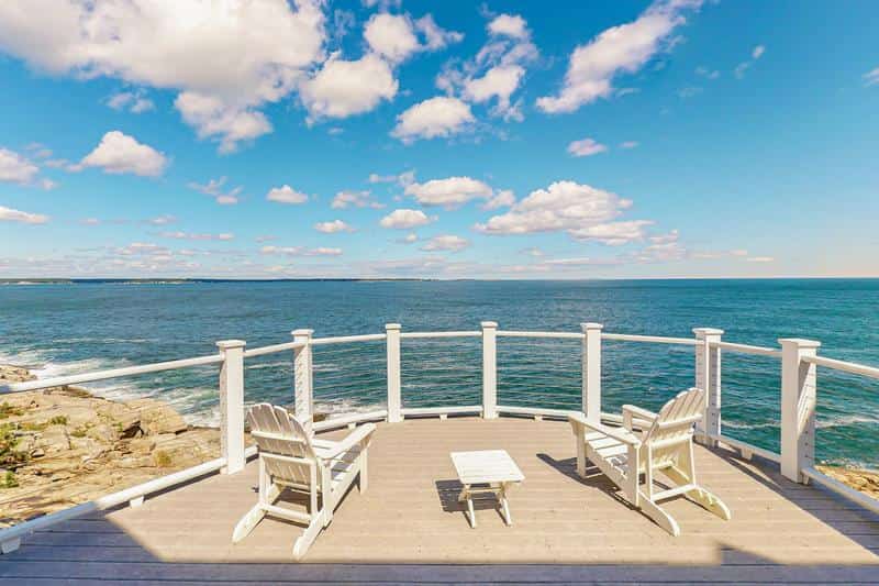 two white adirondack chairs face body of water