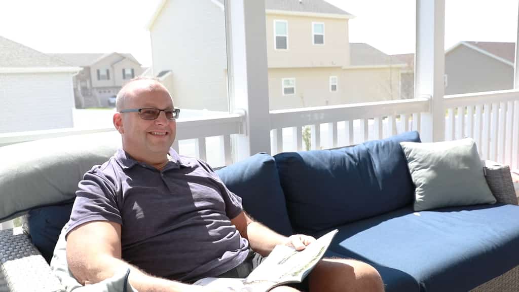 Vacasa homeowner Jon smiles while sitting and reading on the patio of his vacation home