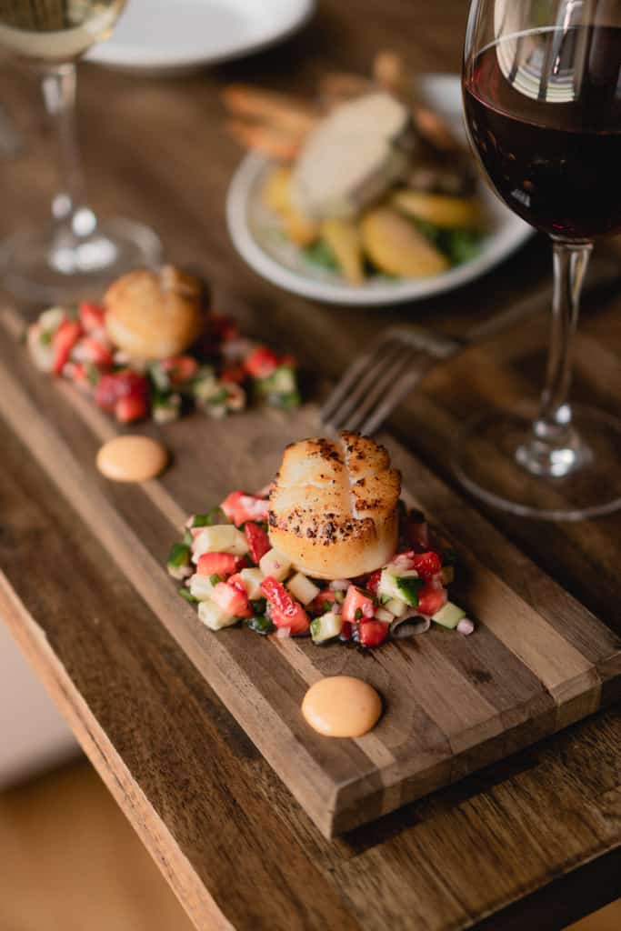 A board with two scallops near a wine class.