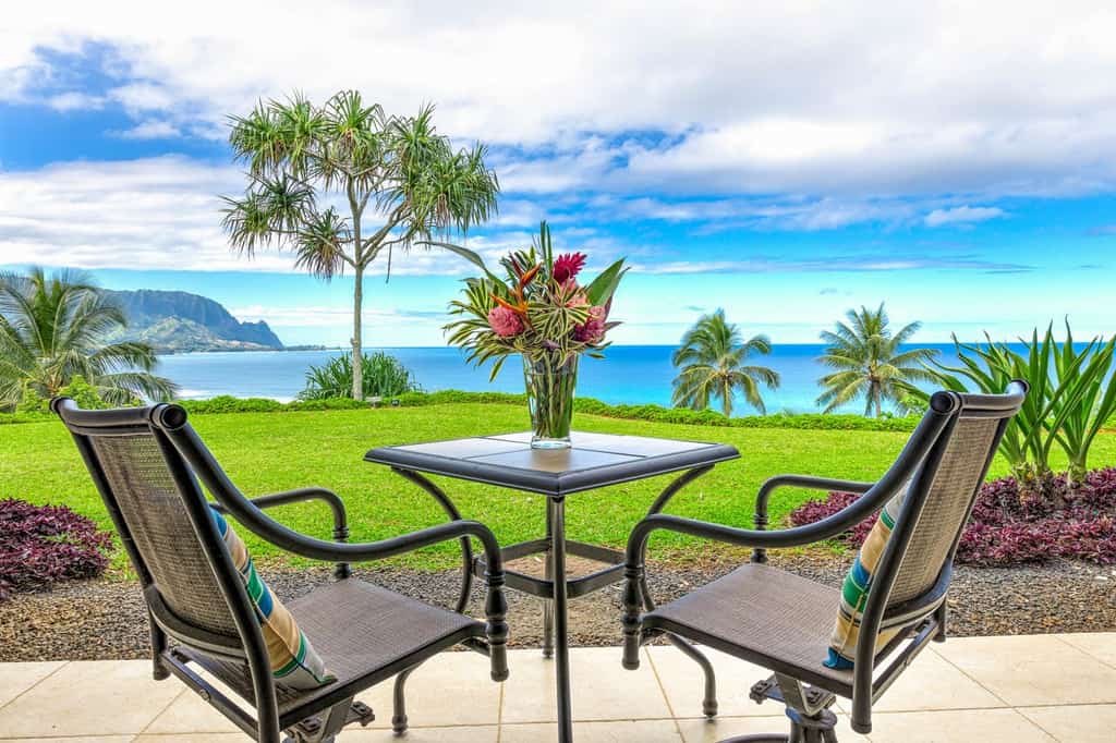 two chairs sitting on a patio overlooking the pacific ocean on kauai