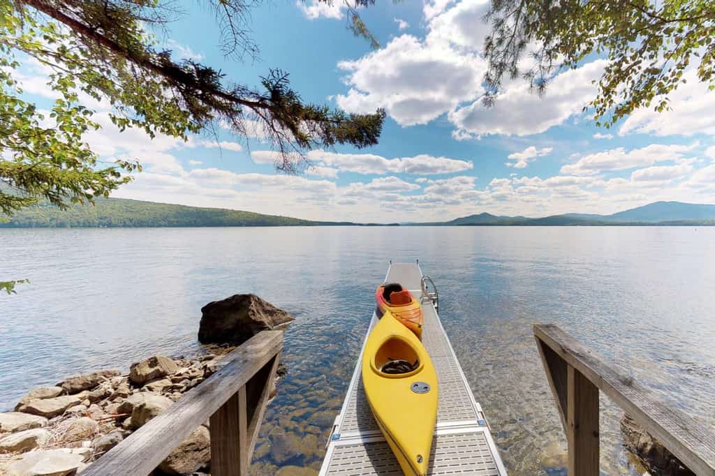 Vacation rental dock with kayaks extending over lake