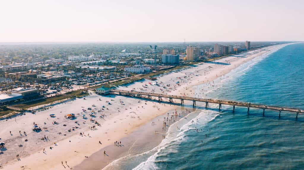 A drone shot of the Jacksonville coastline highlighting the boardwalk and city skyline,