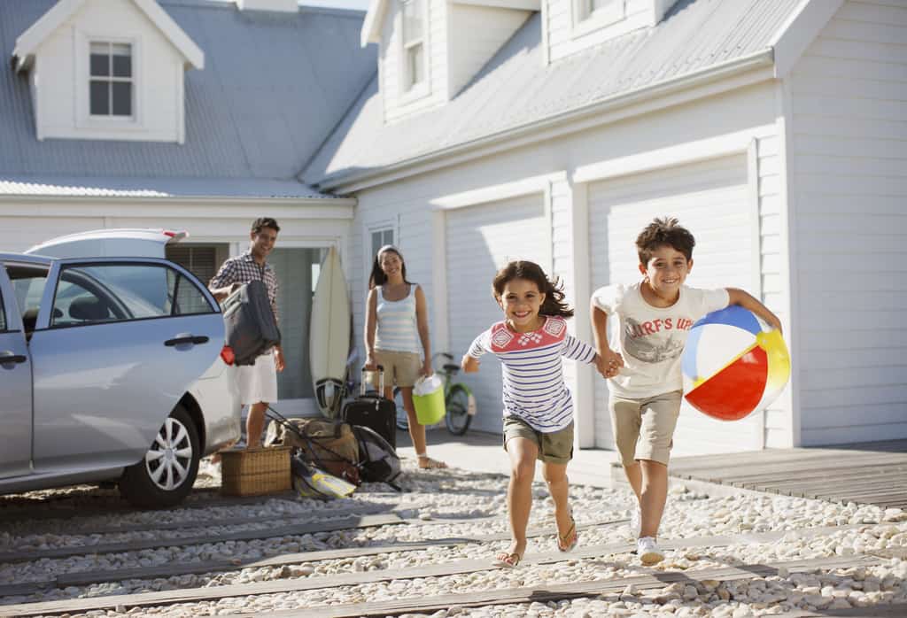 Family loading up car for the beach in vacation rental driveway
