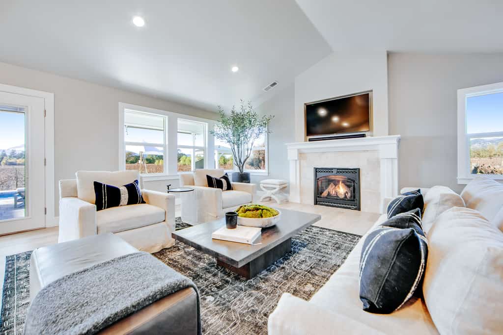 clean living room with white couches, an area rug, and a fireplace