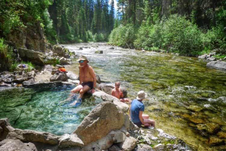 People soaking their feet in a hot spring and river in McCall, ID.