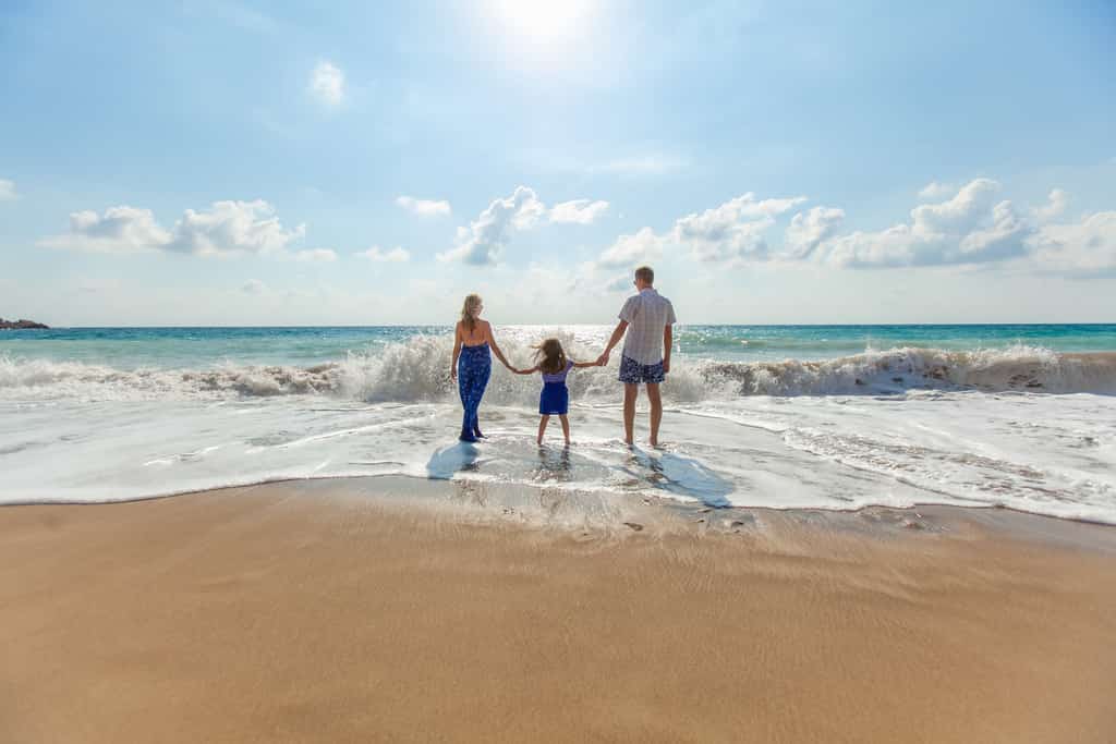 Two parents with a child between them holding hands.