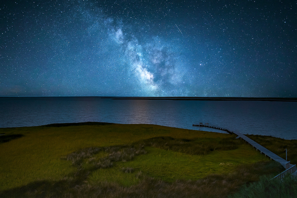The view of the ocean from the shoreline taken at night time.