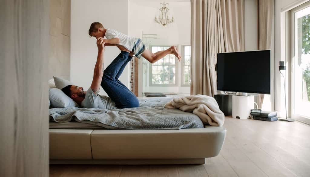 Father raising child in the bed.