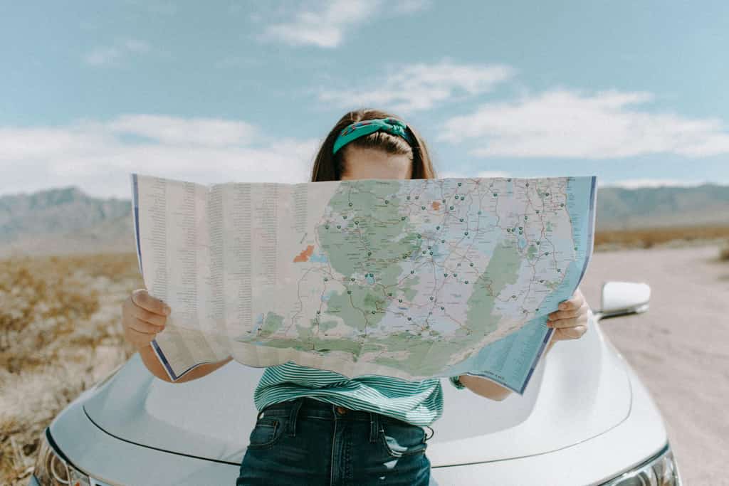 Woman looking at a map while leaning against a car in California.