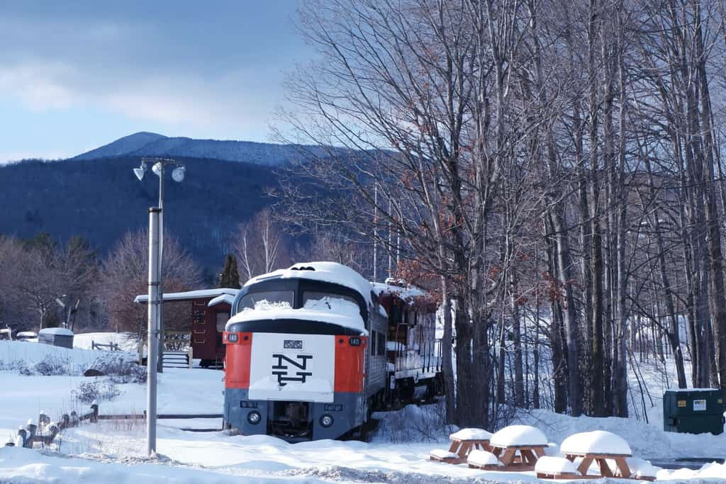 red and white train in new hampshire during winter snow